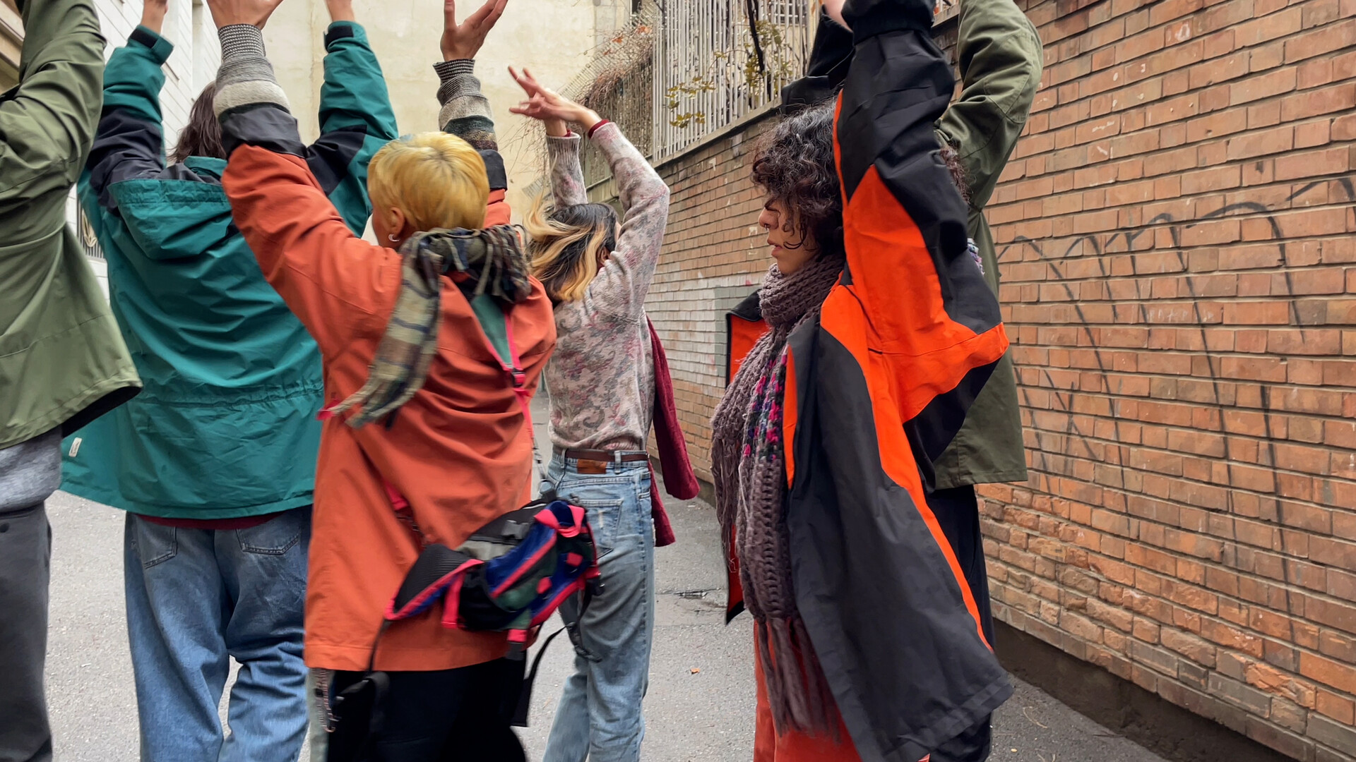 Dancers in a street protest space with arms in air